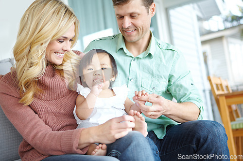 Image of She makes our family complete. A happy couple spending time with their beautiful adopted daughter while at home.