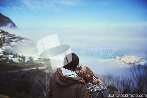 Image of Admiring the view. Rearview shot of an affectionate young couple enjoying a hike in the mountains.