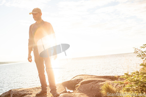 Image of I should come out here more often. a man wearing his backpack while out for a hike on a coastal trail.