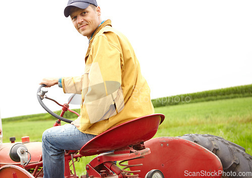 Image of Just an average day at the office. Rearview of a smiling farmer driving his tractor on an open field.