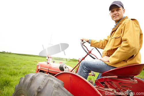 Image of Preparing for a hard days work. A farmer sitting on his tractor and looking at the camera on an open field with copyspace.