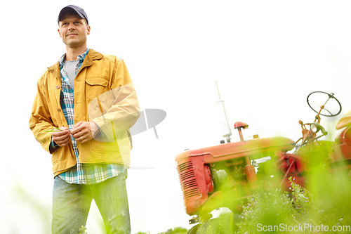 Image of Admiring the view. A farmer standing in a field with his tractor parked behind him - Copyspace.