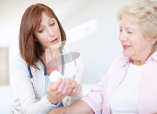 Image of Prescription medication - Senior Care. Mature nurse explains the dosage and side effects of the medication to an elderly female patient.