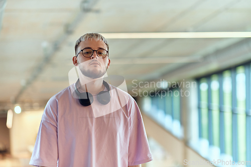 Image of In a contemporary startup office, a modern blond entrepreneur stands, engrossed in his smartphone, epitomizing the dynamic and tech-savvy essence of the modern business world.