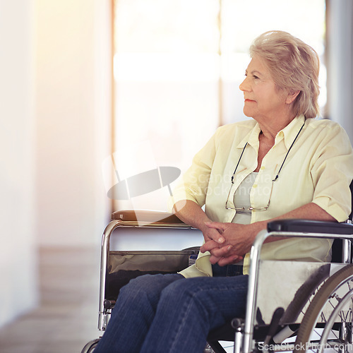 Image of Taking a trip down memory lane. a senior woman looking thoughtful while sitting in a wheelchair at home.