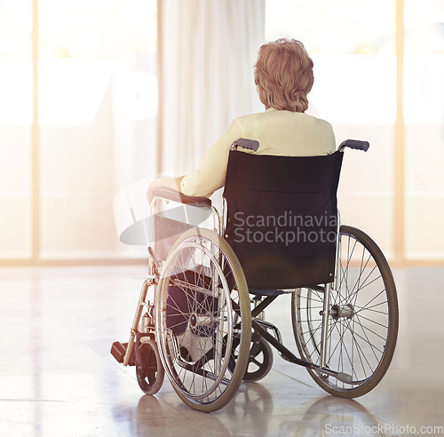 Image of Facing the difficulties of the aging process. Rearview shot of a senior woman sitting in her wheelchair at home.