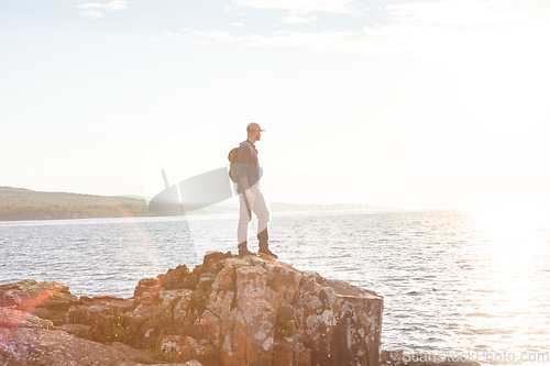 Image of The climb is guaranteed to make you sweat. a man wearing his backpack while out for a hike on a coastal trail.