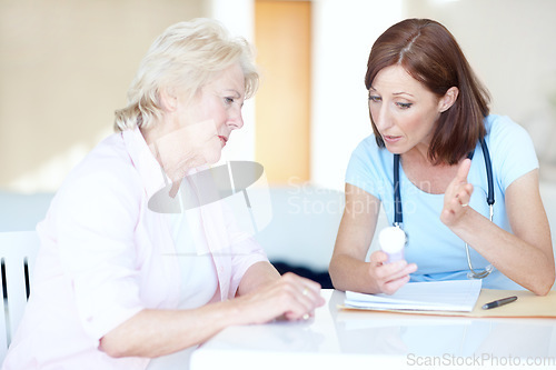 Image of Explaining a solution to her problems - Senior Healthcare. Mature doctor explains an elderly womans prescription medication to her.