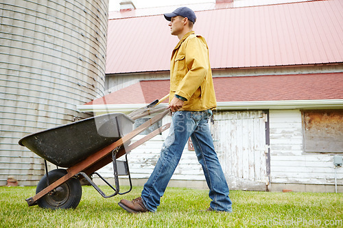 Image of Cleaning up the garden. A man walking outside with his wheelbarrow.