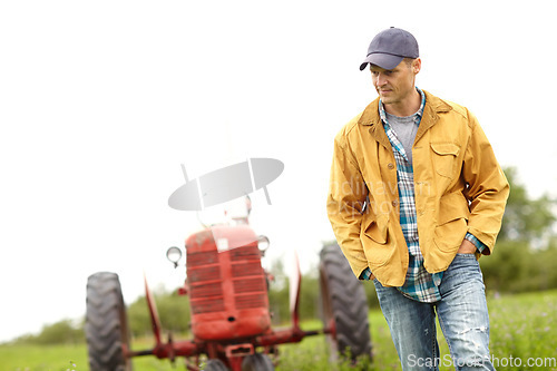 Image of Getting lost in a moment. a farmer walking with his tractor behind him in a field.