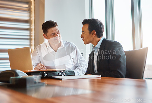 Image of Together we can conquer anything. two businessmen having a discussion while sitting by a laptop.