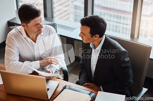 Image of Going into partnership with was the best decision. two businessmen having a discussion while sitting by a laptop.
