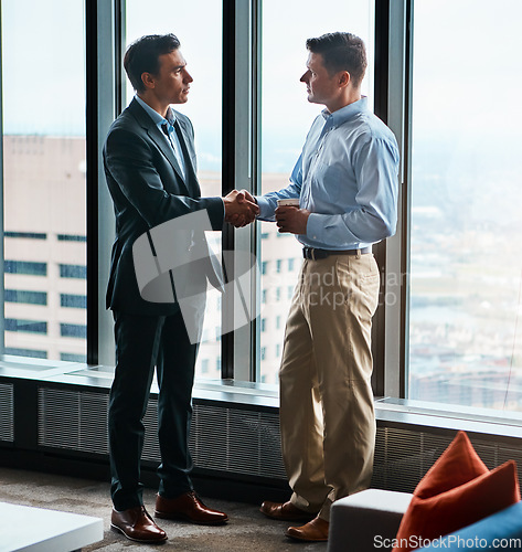 Image of Ready to do business. two businessmen shaking hands in a corporate office.