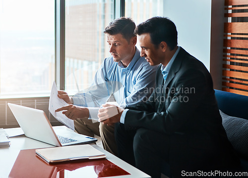 Image of Lets just go over it together. two businessmen having a discussion while sitting by a laptop.