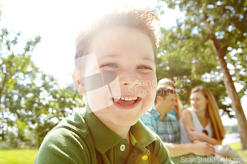 Image of He always has fun with his family. A happy little boy sitting outdoors with his family on a sunny day.