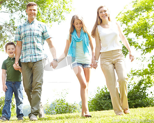 Image of Summer strolls as a family. A happy young family walking through the park together on a summers day.