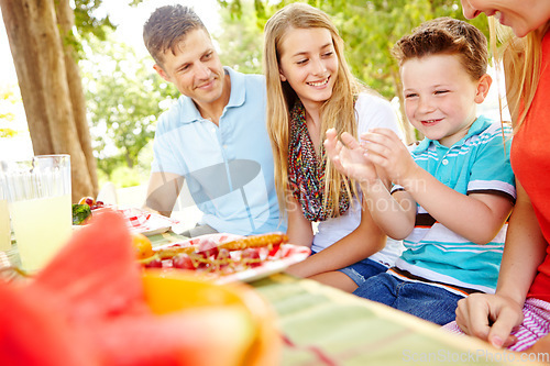 Image of Lets eat. A happy young family relaxing in the park and enjoying a healthy picnic.