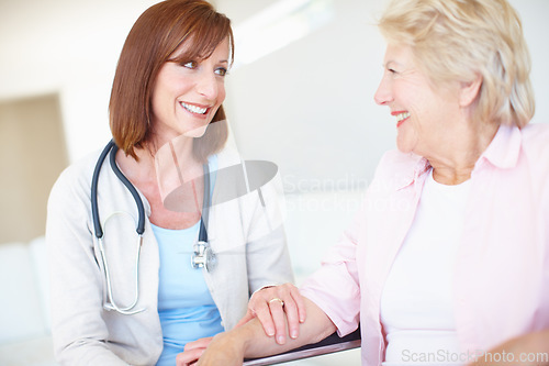 Image of Shes a comfort to her patients. Mature nurse has a friendly conversation with an elderly female patient in a wheelchair.