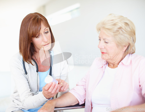 Image of Professional nurse prescribing to her elderly patient. Mature nurse explains the dosage and side effects of the medication to an elderly female patient.