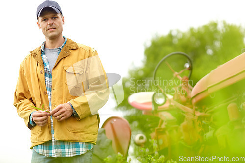 Image of Concerned about my crops. Portrait of a farmer standing next to his tractor in a field.