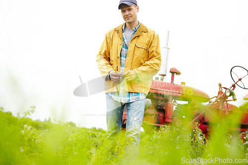 Image of Its just me and my tractor. Portrait of a farmer standing in a field with his tractor parked behind him - Copyspace.