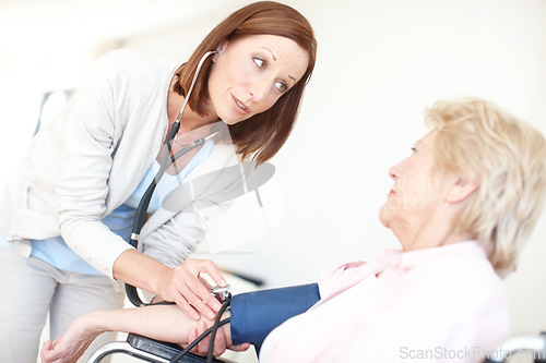 Image of I want to be certain your body isnt under any undue pressure. Mature nurse checks an elderly female patients blood pressure.