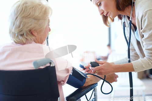 Image of Ensuring her patients blood pressure is normal. Rear-view of a wheelchair-bound elderly patient getting her blood pressure checked by a nurse.