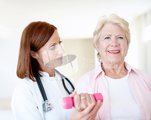 Image of Buoyed by her progress. Determined elderly female is assisted by her nurse as she lifts a dumbbell.