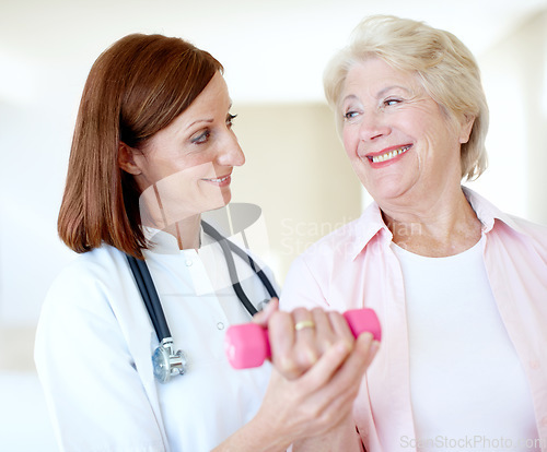 Image of Acknowledging the teamwork it took to recover - Senior Health. Determined elderly female is assisted by her nurse as she lifts a dumbbell.