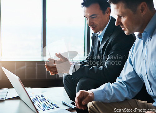 Image of It time to expand our services. two businessmen having a discussion while sitting by a laptop.