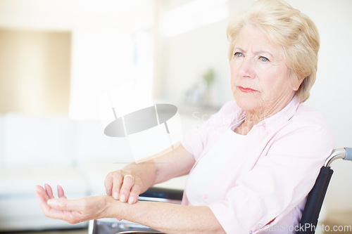 Image of Elderly woman in a wheelchair checking her pulse at the wrist