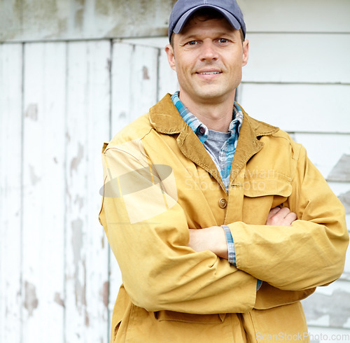 Image of Confident and in charge. Portrait of a smiling man with his arms crossed standing outside a shed.