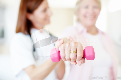 Image of Professional care and rehabilitation - Senior Health. Closeup of a pink dumbbell being lifted by an elderly female assisted by her nurse in background.