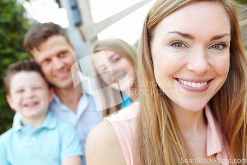 Image of I have the perfect family. Smiling attractive mother with family sitting behind her while outdoors.