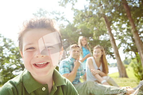 Image of He loves spending time with his family. A happy little boy sitting outdoors with his family on a sunny day.