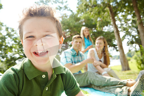 Image of Secure in his familys love. A happy little boy sitting outdoors with his family on a sunny day.