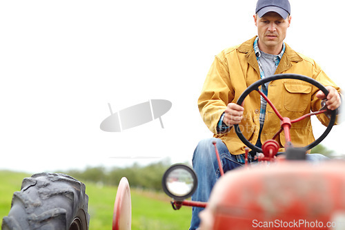 Image of Taking care of the plantation. A farmer driving his tractor on an open field.