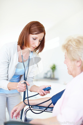 Image of Checking that her blood pressure is normal - Senior Health. Mature nurse checks an elderly female patients blood pressure.