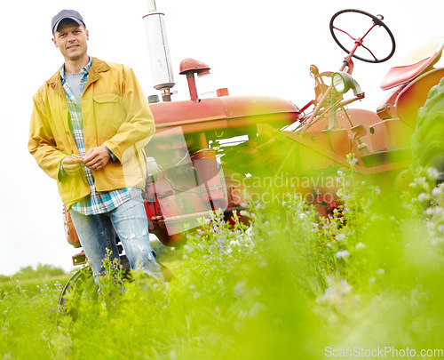 Image of This job is my whole life. Portrait of a smiling farmer standing next to his tractor in a field.