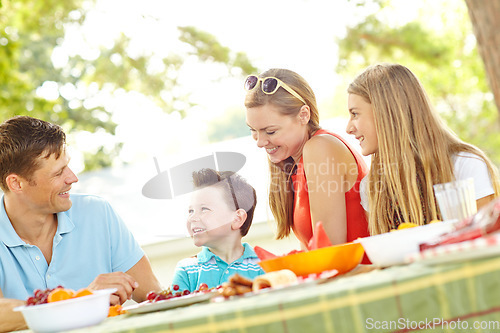 Image of Enjoying a family meal together. A happy young family relaxing in the park and enjoying a healthy picnic.