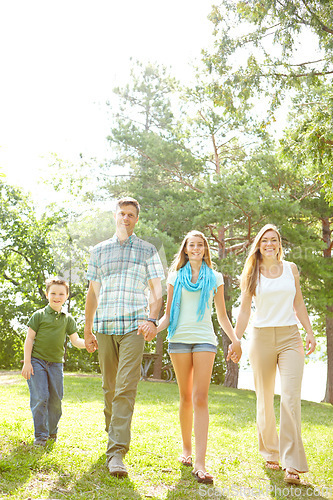 Image of Strolling through the park. A happy young family walking through the park together on a summers day.