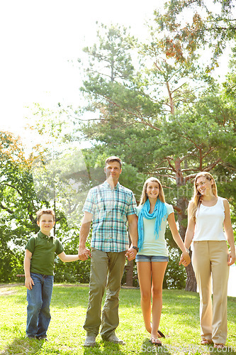Image of Taking a stroll together. A happy young family walking through the park together on a summers day.