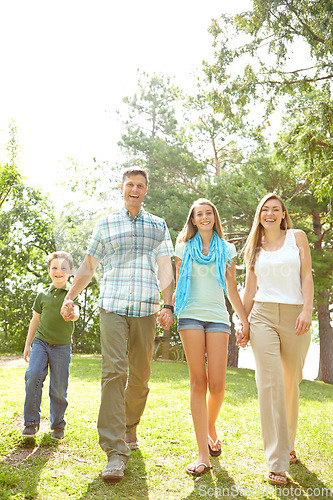 Image of Taking a walk together. A happy young family walking through the park together on a summers day.