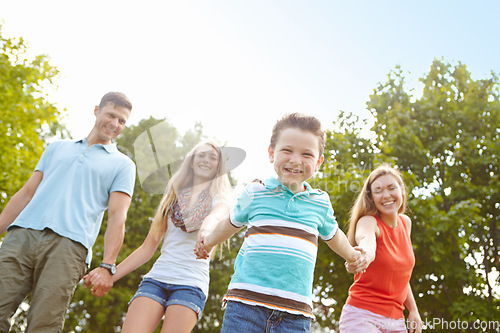 Image of Going for a walk in the park. Low angle shot of a happy family walking hand in hand outdoors.