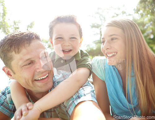 Image of He loves his mom and dad. A happy young family lying on the ground together at the park.