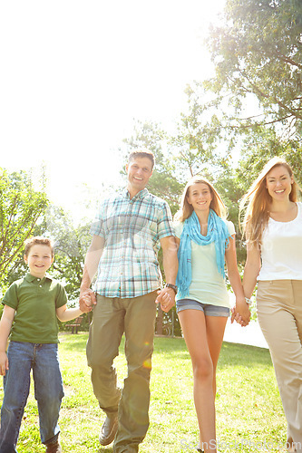 Image of Enjoying a family stroll. A happy young family walking through the park together on a summers day.