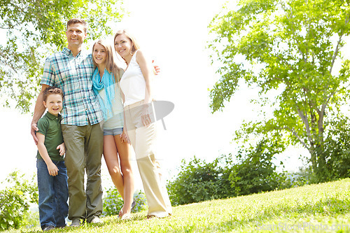 Image of Family moments in the park. A happy family standing together in the park on a summers day.