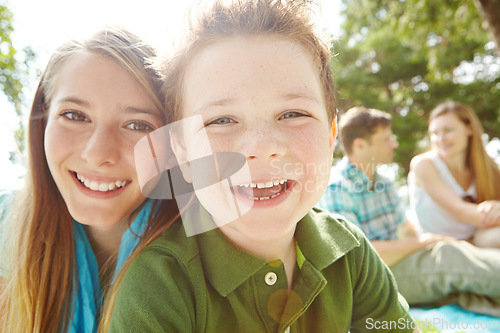 Image of Siblings and the best of friends. A happy little boy sitting outdoors with his family on a sunny day.