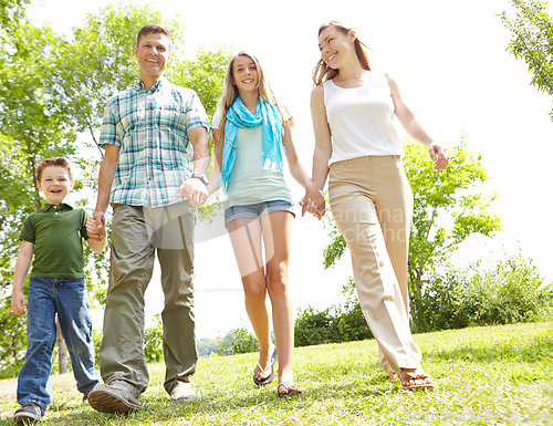 Image of Family time spent outdoors. A happy young family walking through the park together on a summers day.