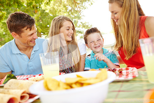 Image of This is delicious. A happy young family relaxing in the park and enjoying a healthy picnic.